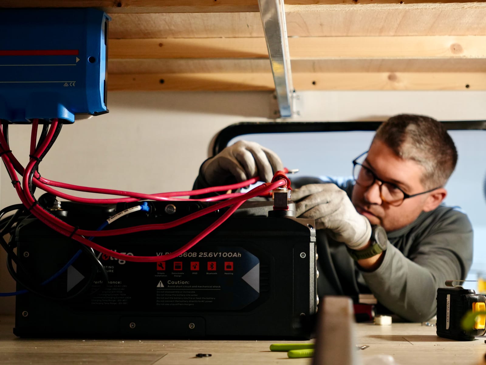 Technician wiring battery cables to a lithium battery inside a cabinet