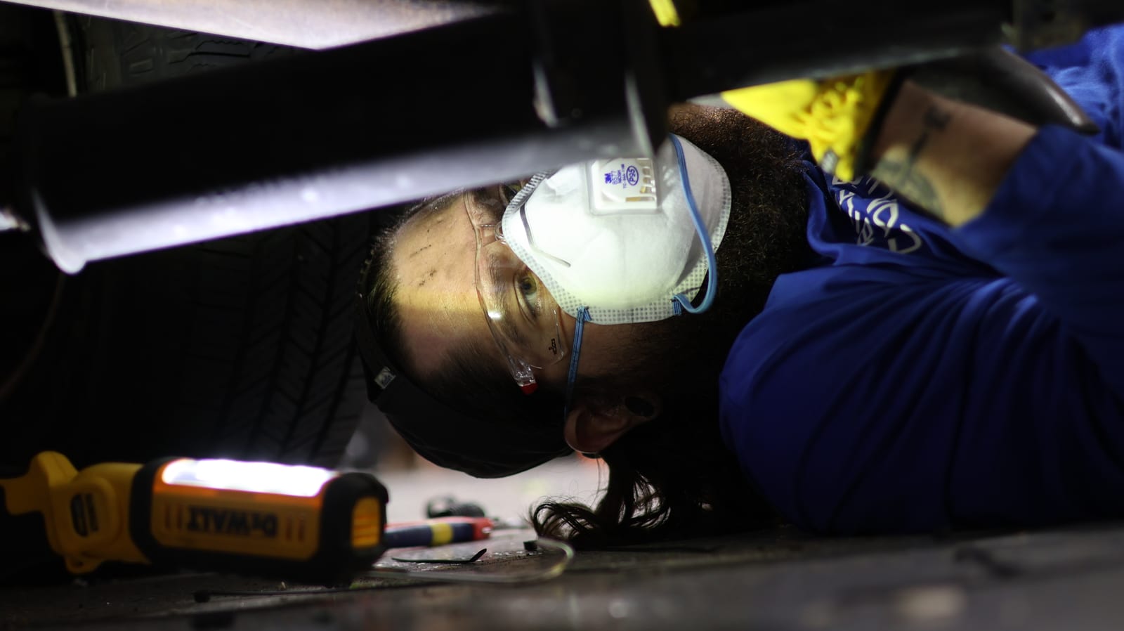 Technician with a headlamp working underneath a vehicle chassis