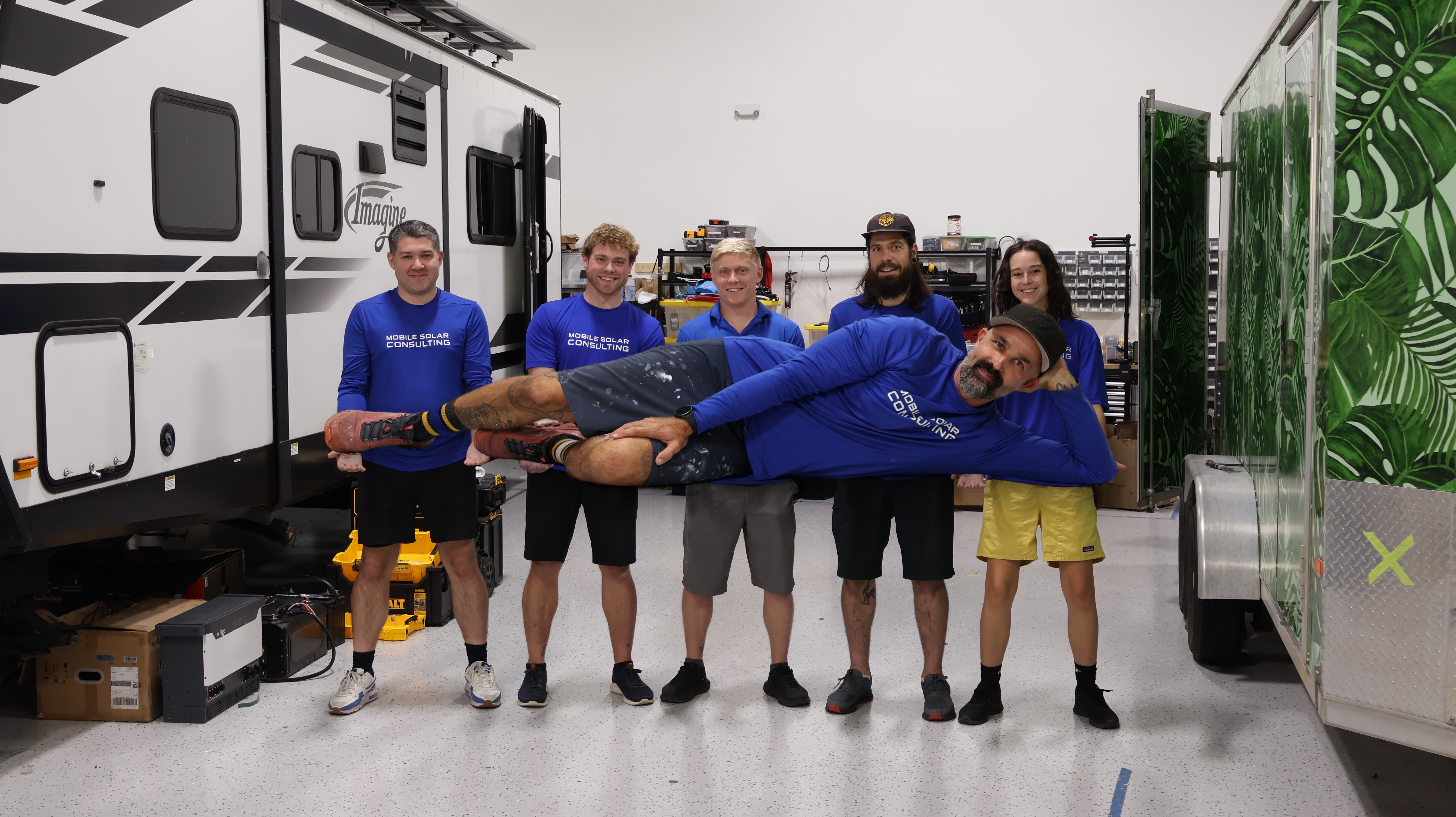 The Mobile Solar Consulting team holding Jesse up in the shop